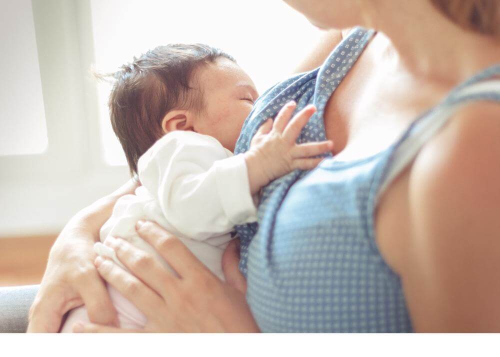 Newborn with eyes closed, breastfeeding