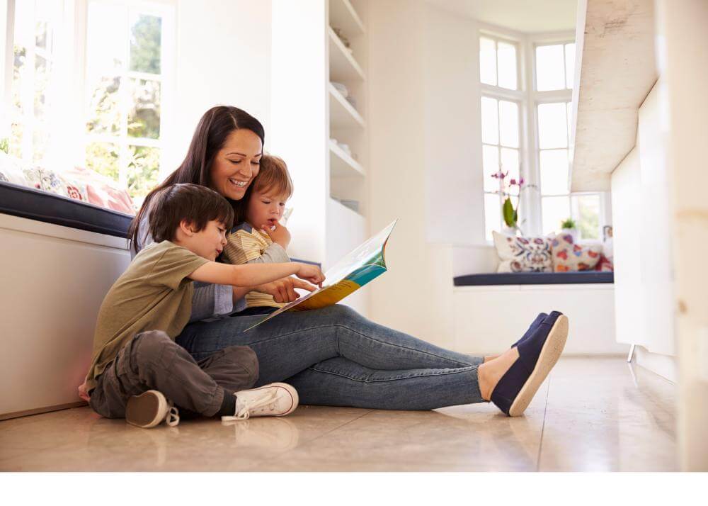 Woman with small child in lap, young boy beside all reading a book