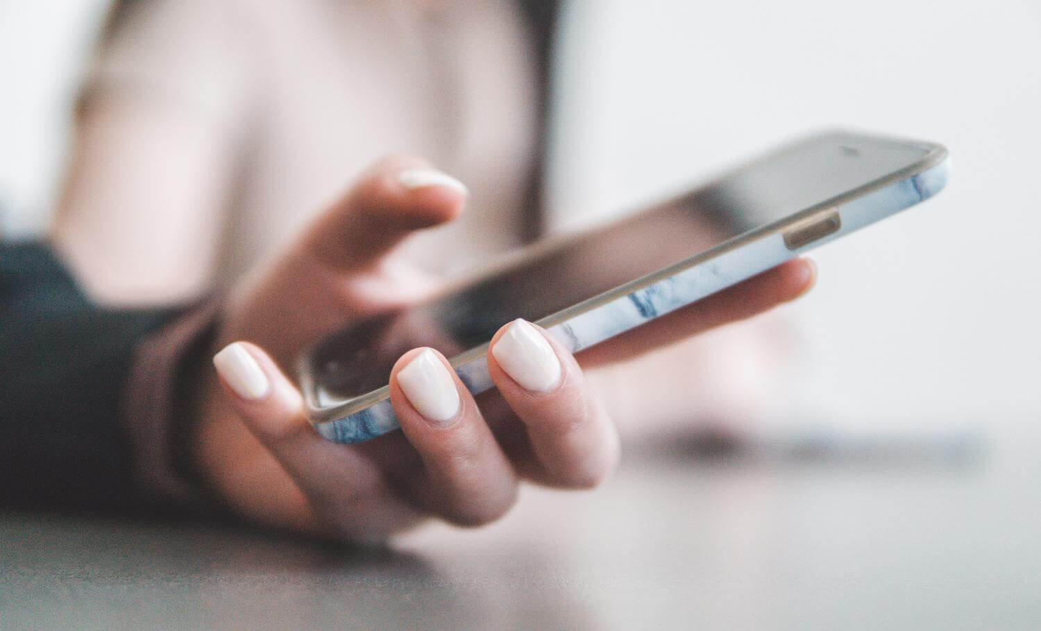 A close up of a woman's hand holding a iPhone.