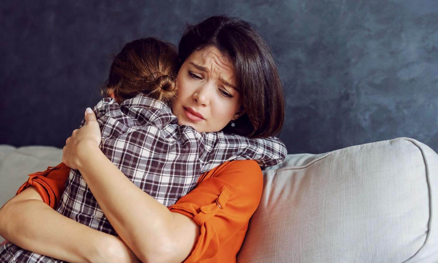 Woman with a worried expression hugging young child