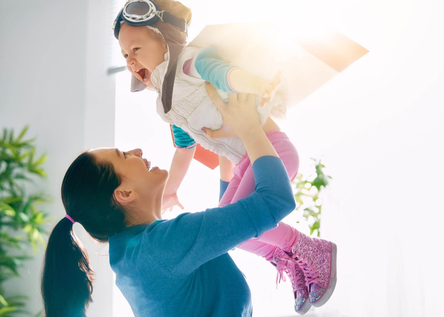 Woman holding young child up in the air, both laughing