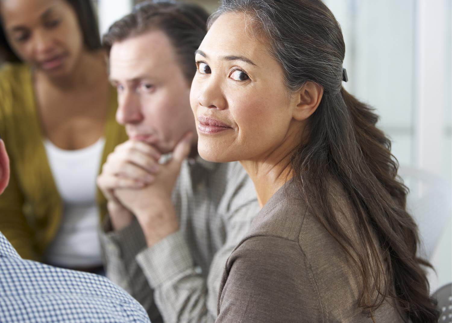 Woman looking over shoulder to camera; man and woman in background