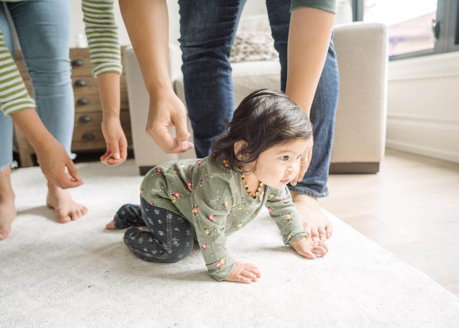 Baby crawling with adults leaning down behind