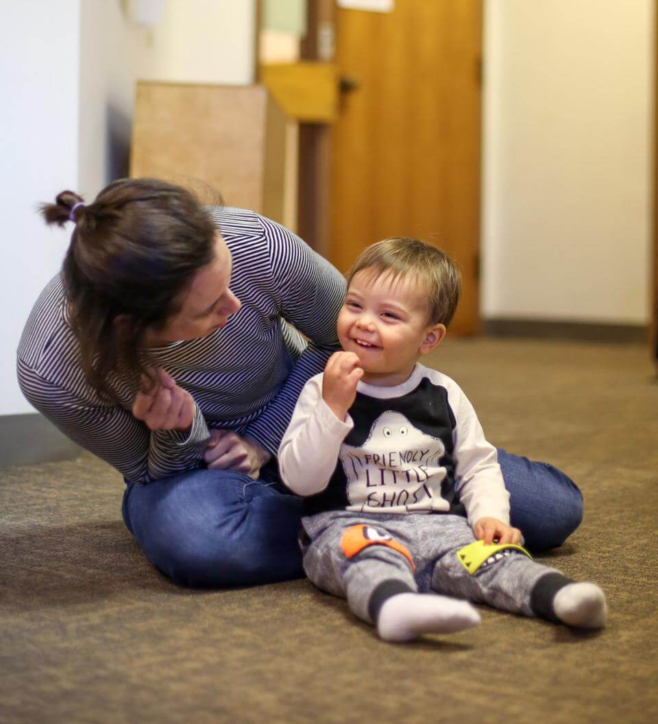 Woman sitting behind young child who is smiling