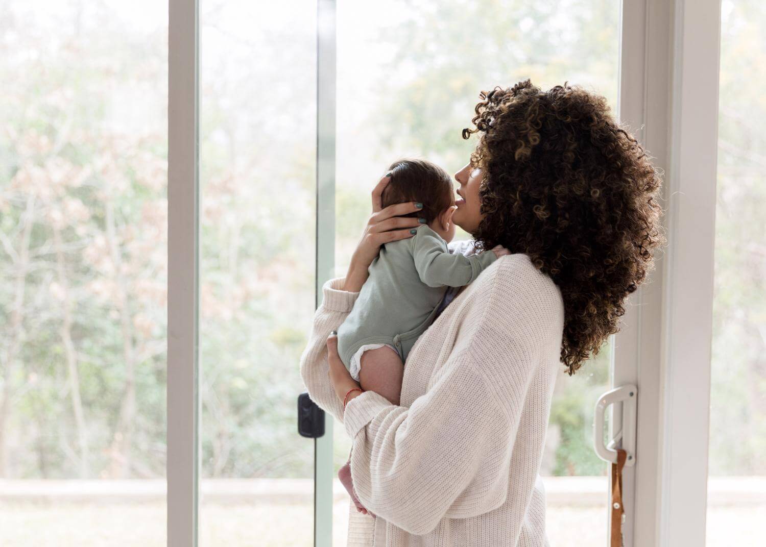 Profile photo of woman holding baby, windows in background