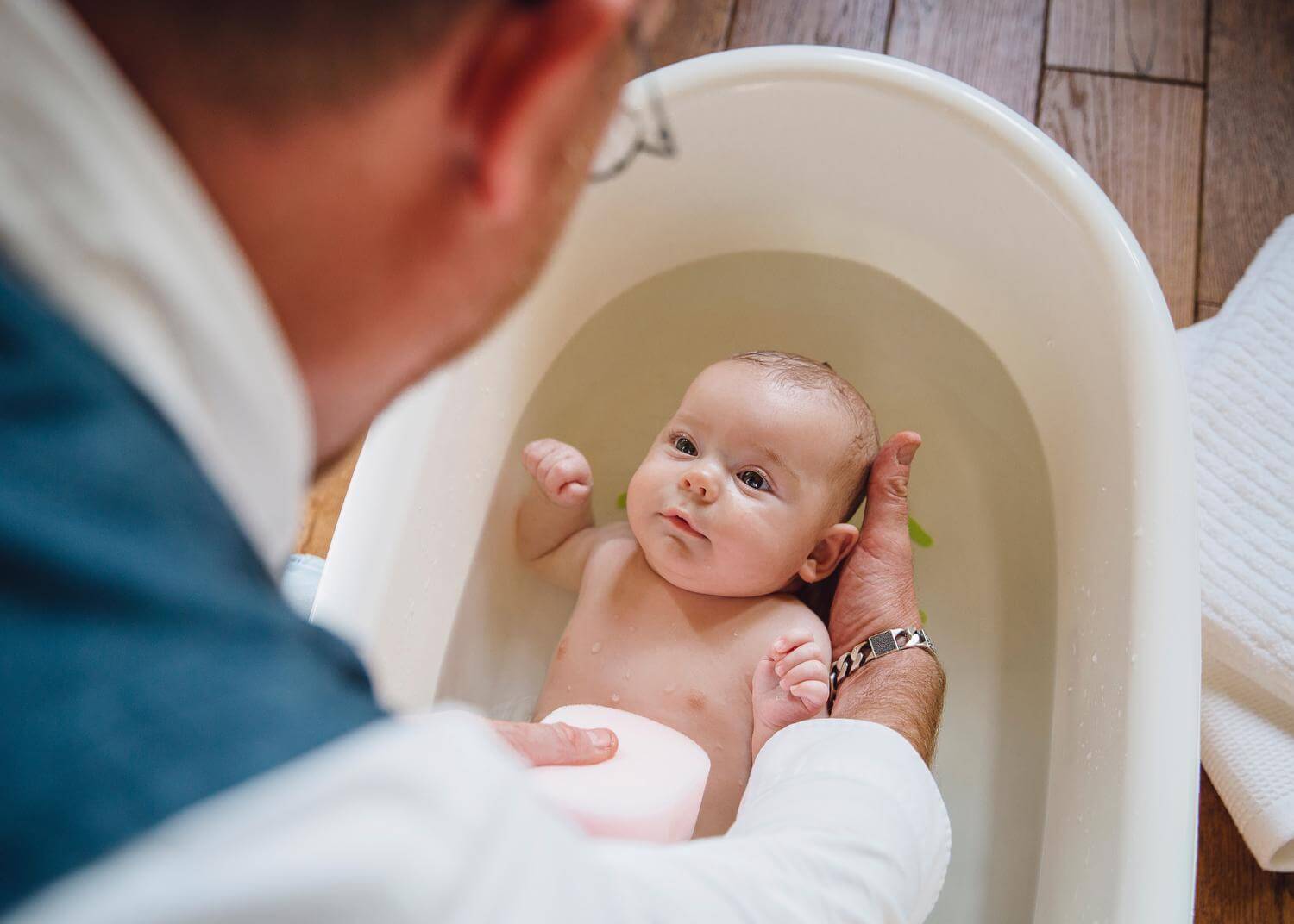 Dad leans over baby, giving them a bath