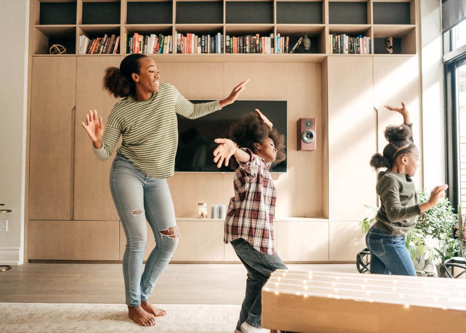 Black woman and two young black children dancing, smiling