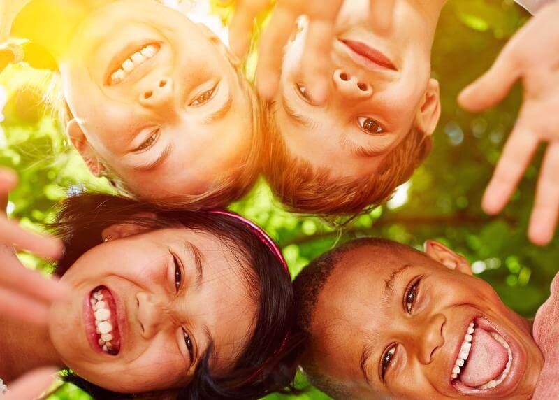 Four children looking down at camera all smiling