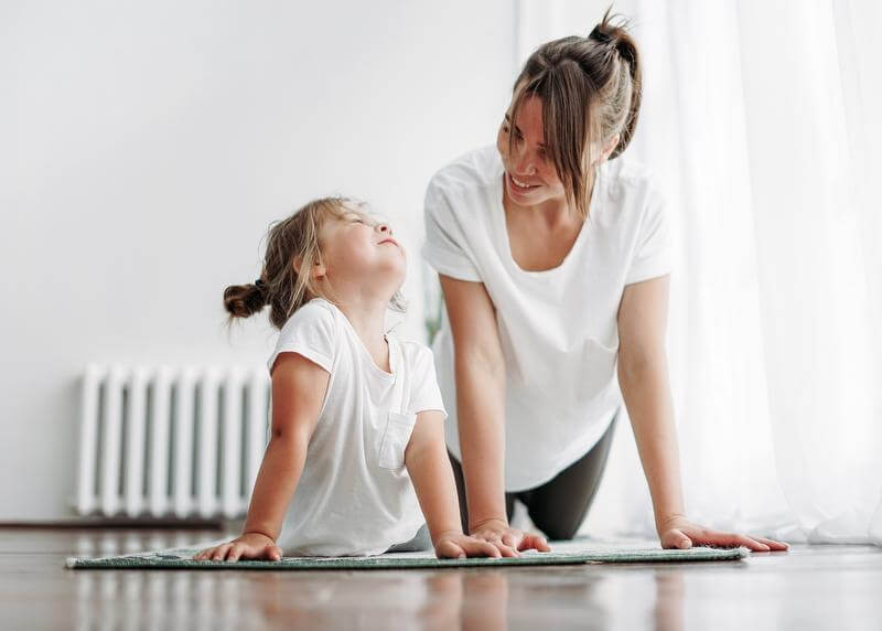 Woman and young child in a cobra yoga position side by side